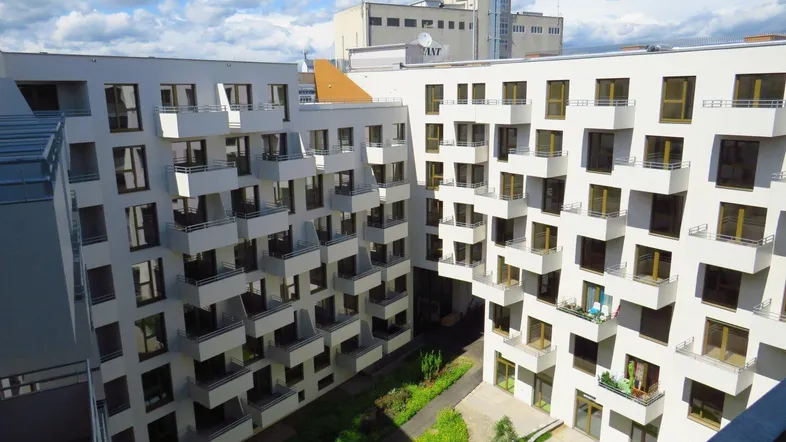 Blick auf den begrünten Innenhof eines modernen Wohnkomplexes mit zahlreichen Balkonen und hellen Fassaden.