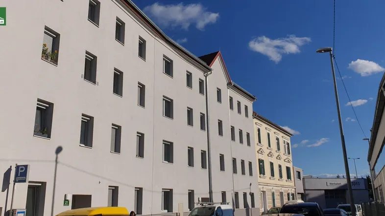 Ansicht der modernen Gebäudefassade mit zahlreichen Fenstern und klarem blauen Himmel.