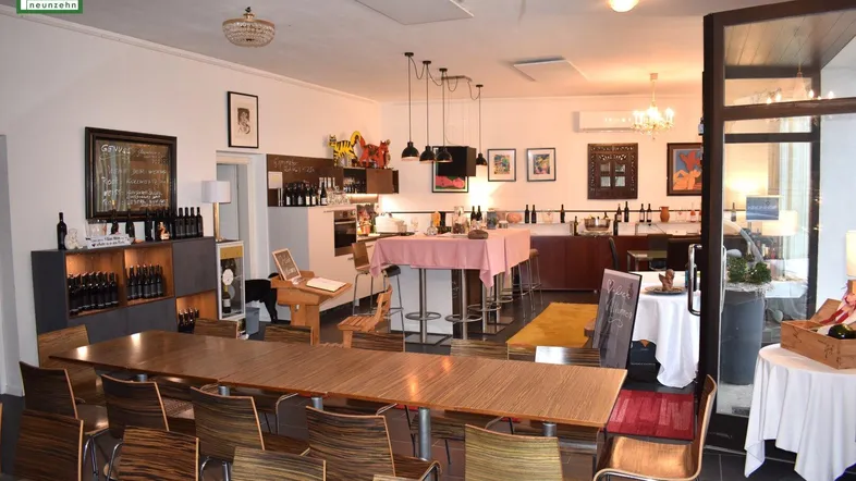 Geräumiger Innenbereich mit langen Holztischen, Bar und Weinflaschenregalen, ideal für Verkostungen oder Veranstaltungen.