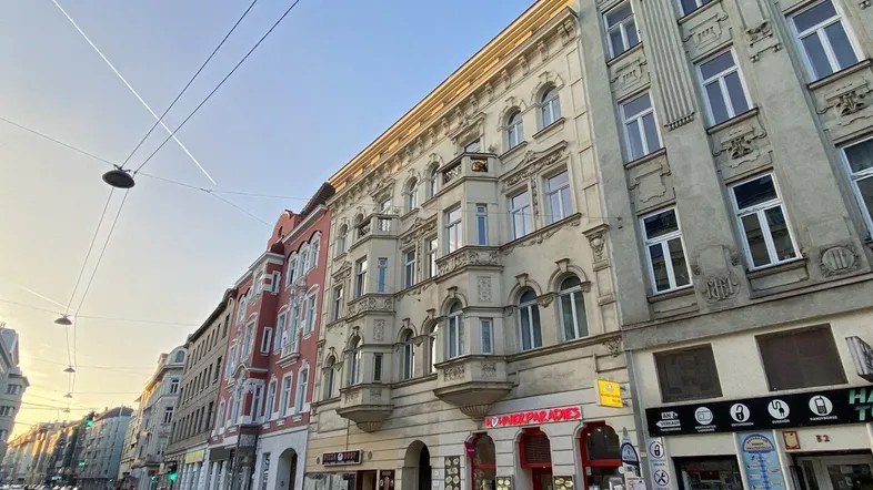 Blick auf eine belebte Stadtstraße mit historischen Gebäuden und Geschäften unter klarem Himmel.