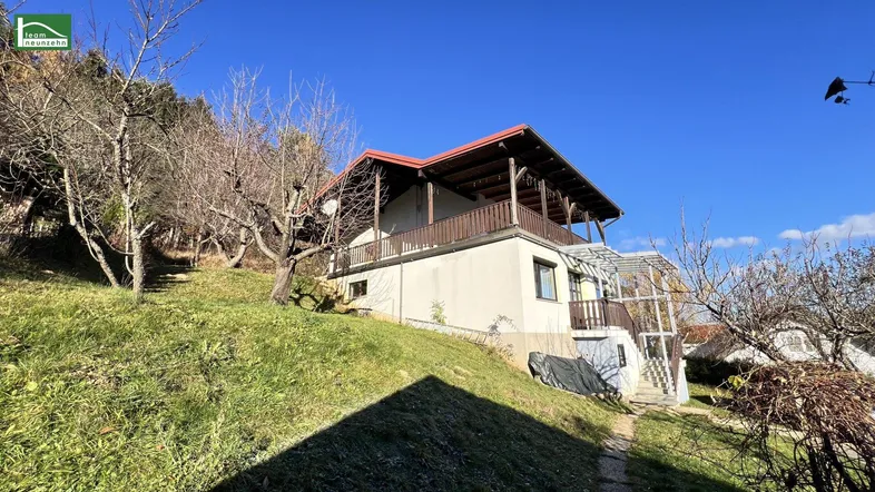 Das Haus liegt an einem Hang mit viel Grün und bietet eine ruhige Wohnlage.
