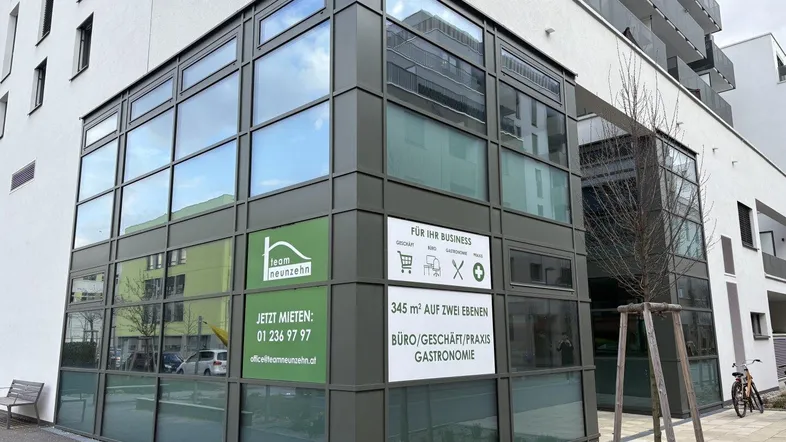 Moderne Geschäftsfassade mit großen Glasfenstern und Mietanzeigen für Büro- und Praxisflächen.