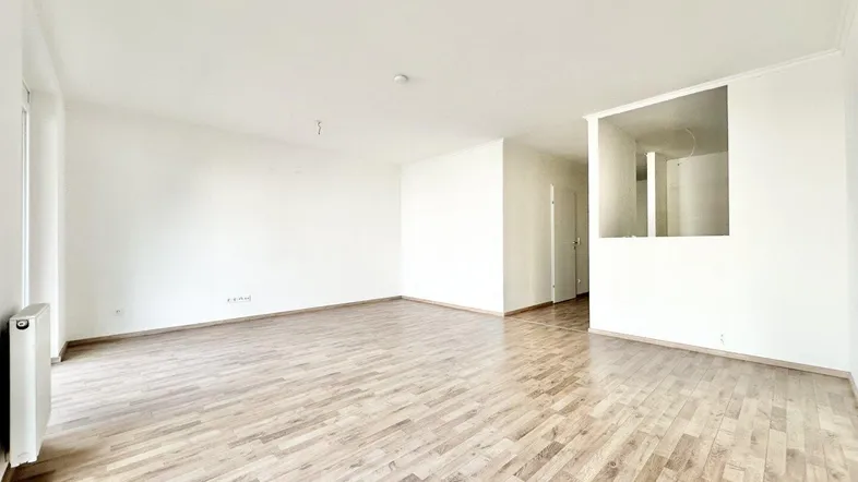 Helles, leeres Zimmer mit Laminatboden und weißen Wänden, bereit zur individuellen Gestaltung.