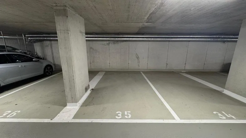 Tiefgaragenstellplatz mit Betonwänden und -decke in einer modernen Anlage.