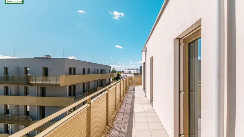 Lange, sonnige Terrasse mit Fliesen und modernem Geländer, ideal für Entspannung im Freien mit Stadtblick.