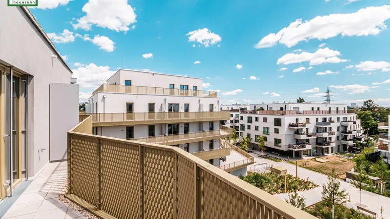 Weitläufiger Balkon mit moderner Brüstung und Aussicht auf die gepflegte Wohnanlage und den blauen Himmel.