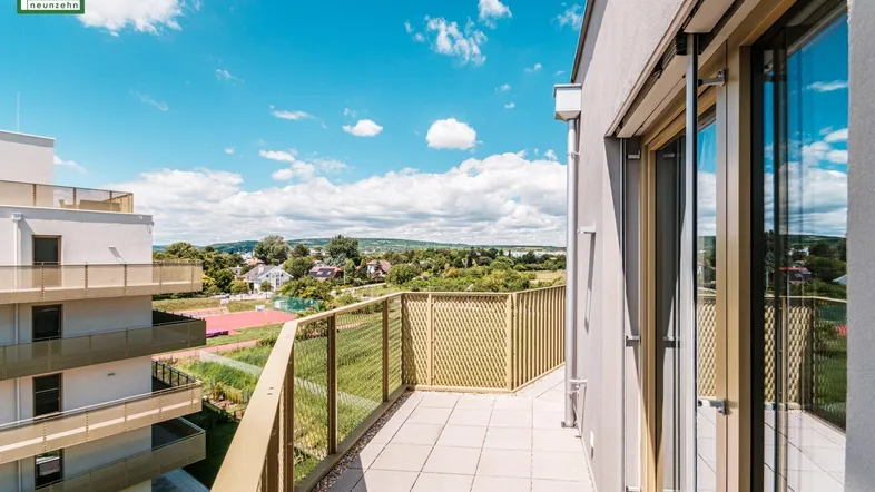 Geräumiger Balkon mit Fliesenboden und weitem Blick ins Grüne und auf die Umgebung.