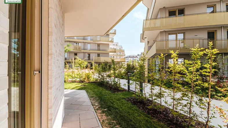 Gepflegter Gartenbereich mit Terrasse und junger Bepflanzung vor der modernen Wohnanlage.