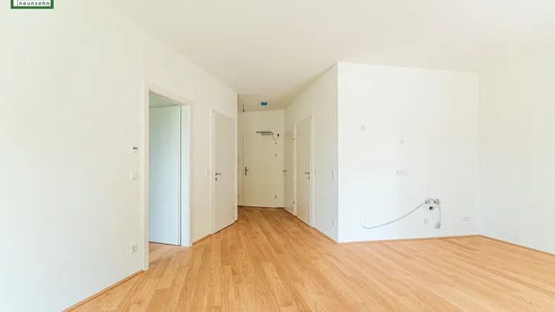 Helle Diele mit Holzboden und Zugang zu mehreren Zimmern in einem Neubau.