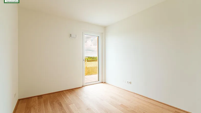Helles Zimmer mit Holzboden und Zugang zu einem Balkon, ideal als Schlaf- oder Arbeitszimmer.
