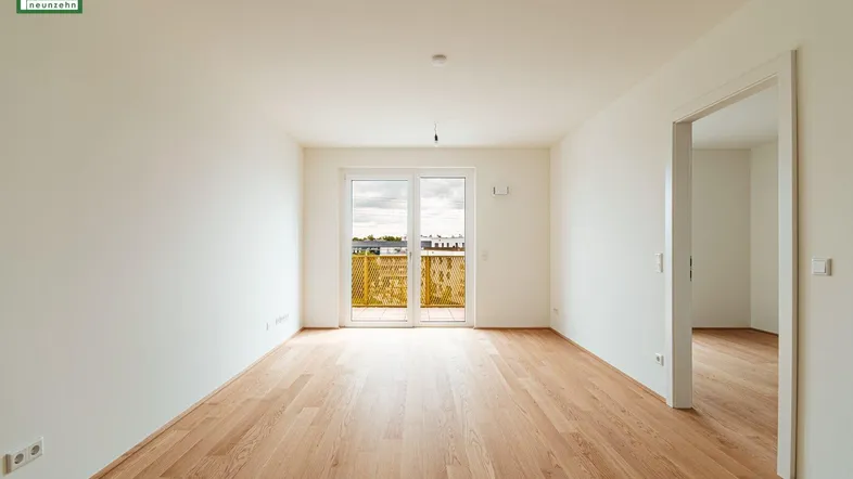 Helles, leeres Zimmer mit Holzboden und Zugang zu einem Balkon, bereit zur individuellen Gestaltung.