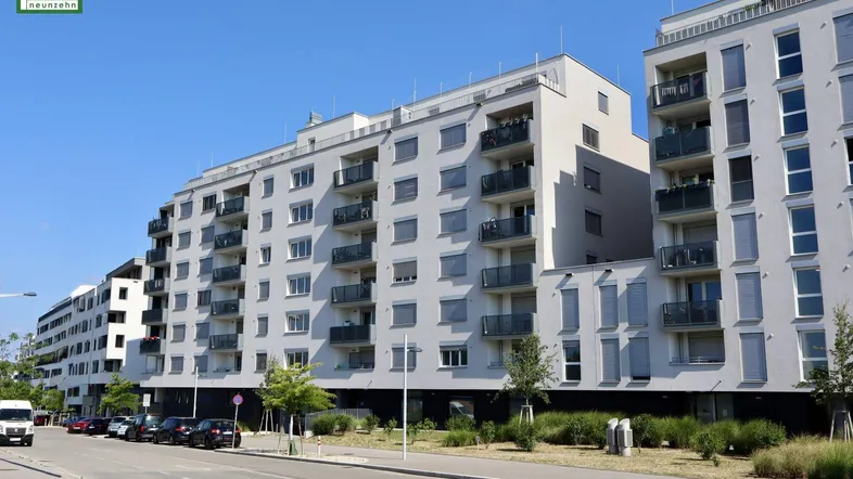 Moderne Wohngebäude mit vielen Balkonen und großen Fenstern an einer städtischen Straße.