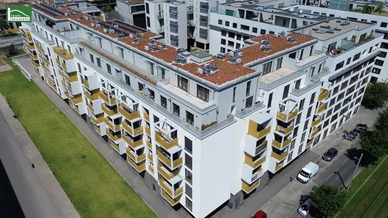 Moderne Wohnanlage mit vielen Balkonen und begrünten Dächern in städtischer Umgebung.