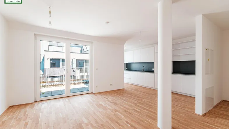 Heller, offener Wohn- und Essbereich mit Holzboden und Zugang zu einem Balkon.