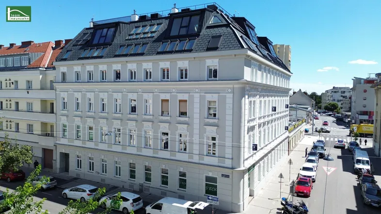 Gesamtansicht des sanierten Altbaus mit modernem Dachgeschoss und umliegender Straße.