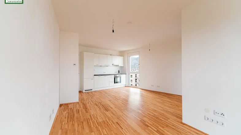 Helles, offenes Wohnzimmer mit integrierter Küche und Parkettboden, ideal für modernes Wohnen.