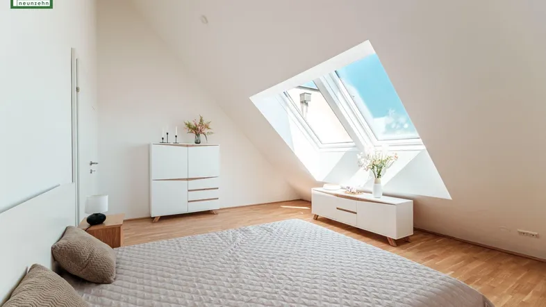 Helles Schlafzimmer im Dachgeschoss mit Holzboden und großen Dachfenstern für viel Tageslicht.