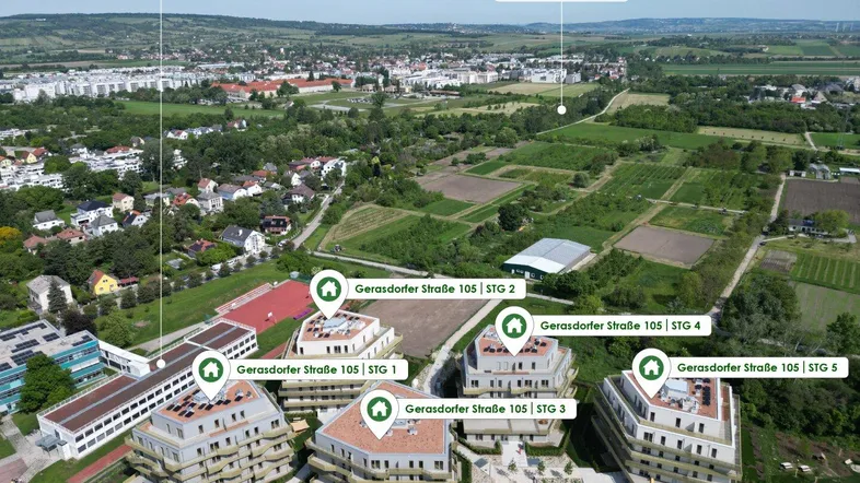 Weitläufige Luftaufnahme eines Wohnkomplexes eingebettet in eine grüne Umgebung mit Feldern und einem Kanal.