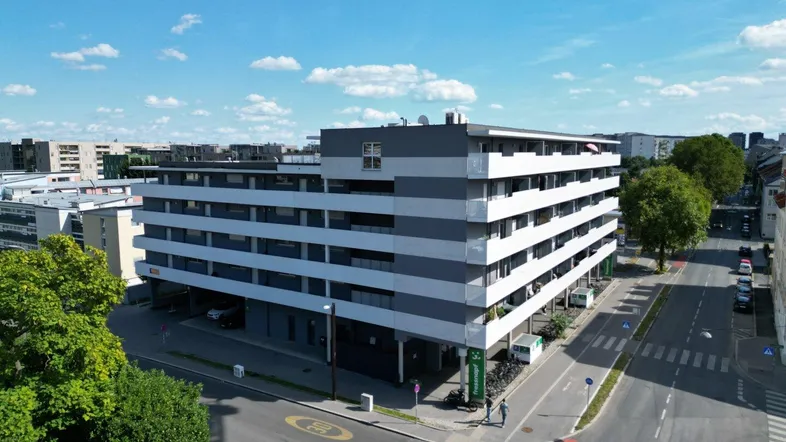 Modernes Mehrfamilienhaus mit klarer Architektur und mehreren Etagen in städtischer Umgebung.