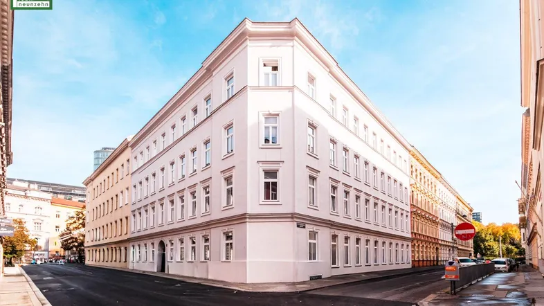 Historisches Eckgebäude mit klassischer Architektur und vielen Fenstern in städtischer Umgebung.