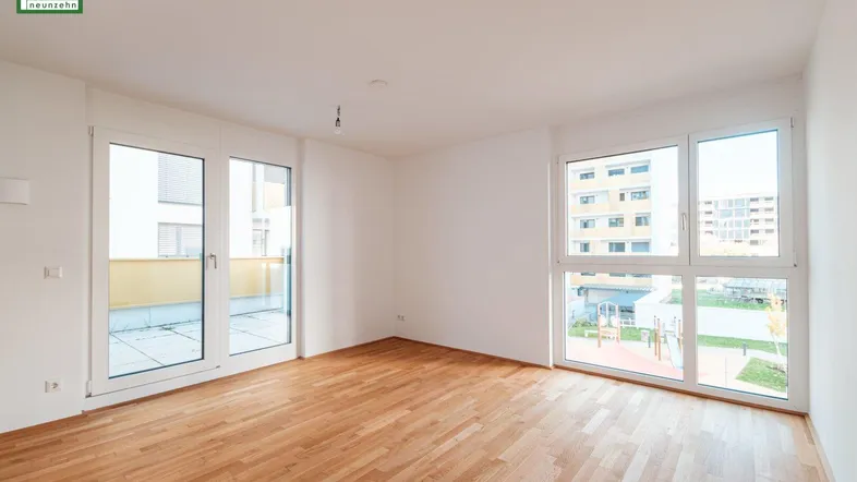 Helles, leeres Zimmer mit Holzboden und großen Fenstern, bietet Zugang zu einer Terrasse.