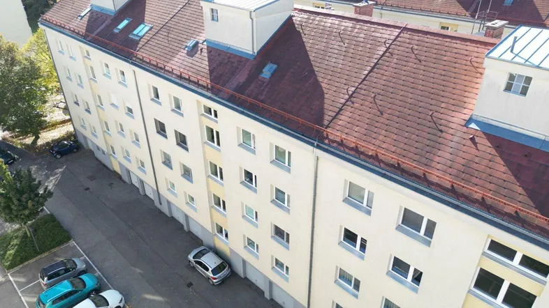 Luftaufnahme eines Wohngebäudes mit Satteldach und Parkplätzen im Freien.