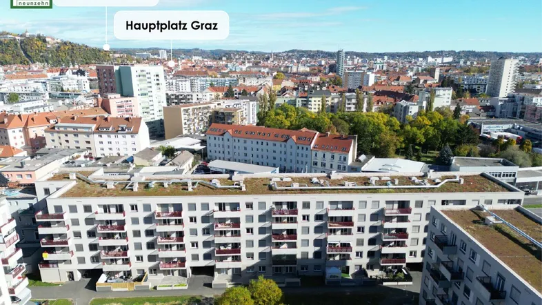 Panoramablick auf Wohngebäude mit begrüntem Dach und die Grazer Stadtlandschaft mit markanten Wahrzeichen.