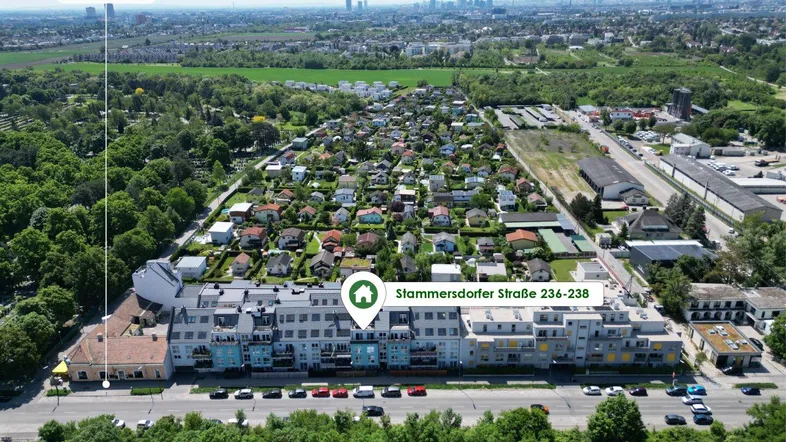 Luftaufnahme eines modernen Wohnkomplexes mit grüner Umgebung und Blick auf die Stadt.