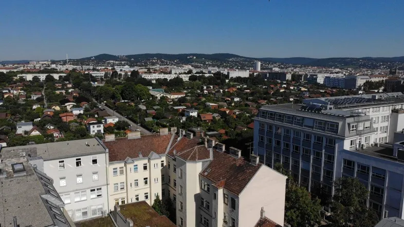 Panoramablick über städtische Dächer und grüne Flächen mit weiter Fernsicht.