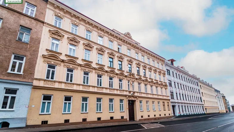Historisches Mehrfamilienhaus mit reich verzierter Fassade an einer städtischen Straße.