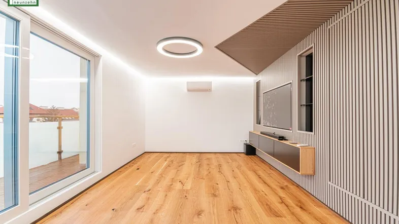 Helles Wohnzimmer mit Holzboden, modernen Leuchten und Zugang zu einer Terrasse.