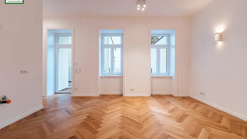 Helles, geräumiges Zimmer mit Fischgrätparkettboden und Zugang zu einem Balkon oder einer Terrasse.