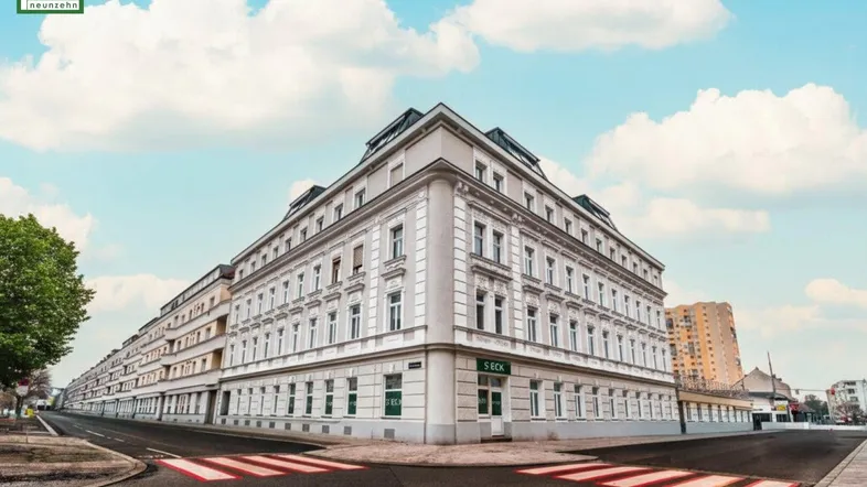 Elegantes Eckgebäude mit klassischer Architektur und vielen Fenstern in urbaner Umgebung.