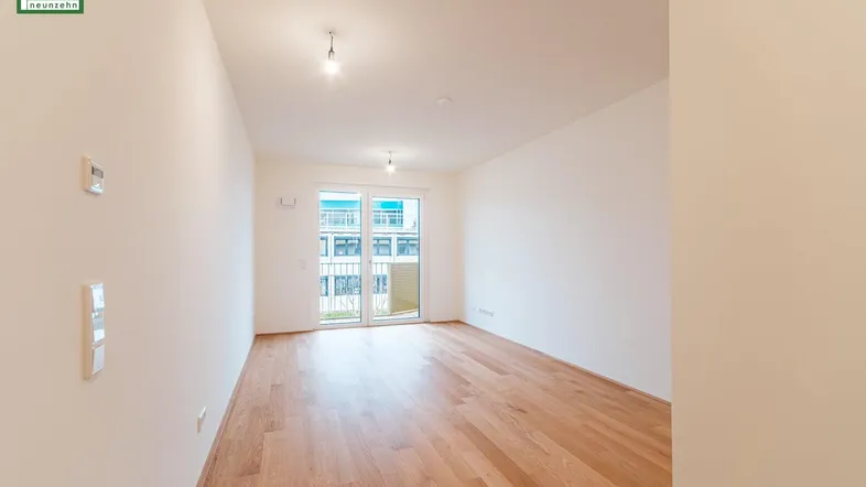 Helles, unmöbliertes Zimmer mit Holzboden und Zugang zu einem Balkon, ideal für Wohnzwecke.