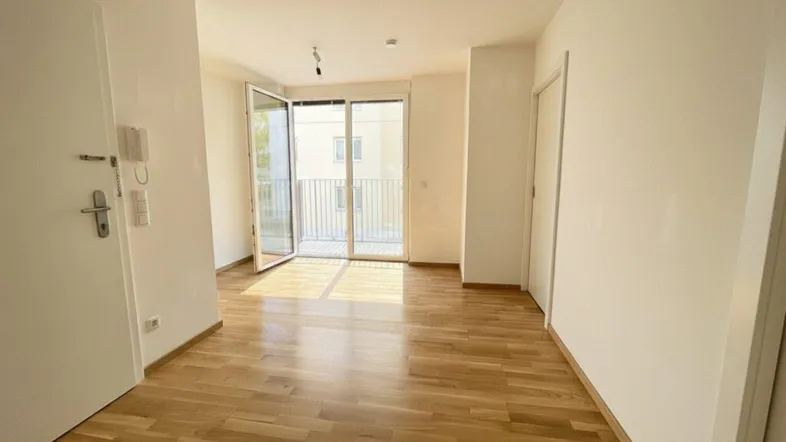 Helles, leeres Wohnzimmer mit Parkettboden und Zugang zu einem Balkon, ideal für neue Einrichtungsideen.