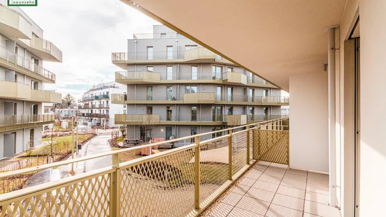 Heller Balkon mit Weitblick über die moderne Wohnanlage und die angrenzende Natur.