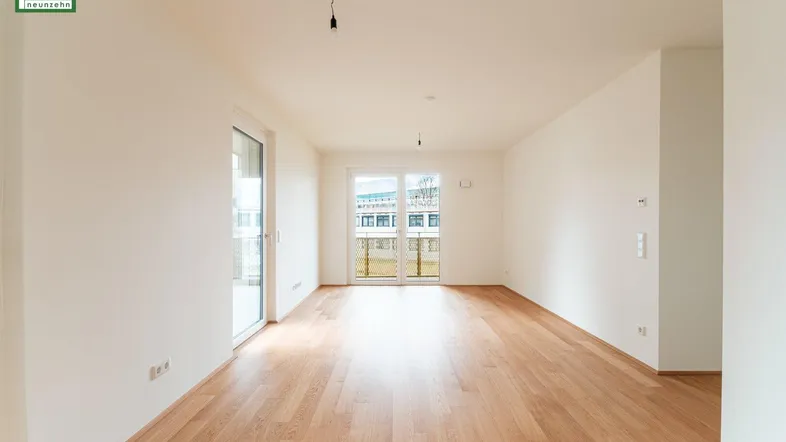 Helles, leeres Zimmer mit Holzboden und Zugang zu einem Balkon, ideal für individuelle Gestaltung.