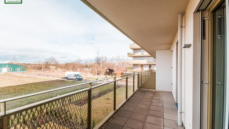 Langer Balkon mit Fliesenboden und Metallgeländer, bietet einen weiten Blick ins Grüne.
