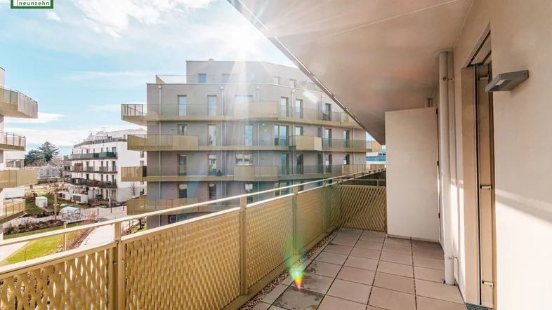 Sonniger Balkon mit Fliesen und Blick auf die umliegenden modernen Gebäude.
