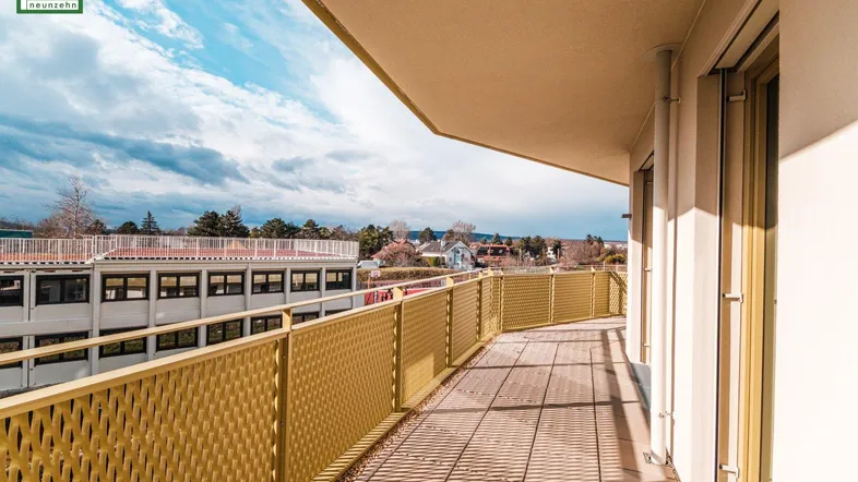 Langer Balkon mit gelbem Geländer und Fliesenboden, bietet einen weiten Blick auf die Umgebung.