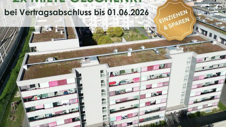 Luftaufnahme eines modernen Mehrfamilienhauses mit begrünten Dächern und Balkonen in städtischer Umgebung.