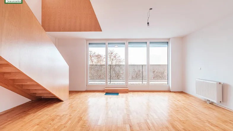 Helles Wohnzimmer mit Parkettboden, großen Fenstern und Zugang zu einem französischen Balkon.