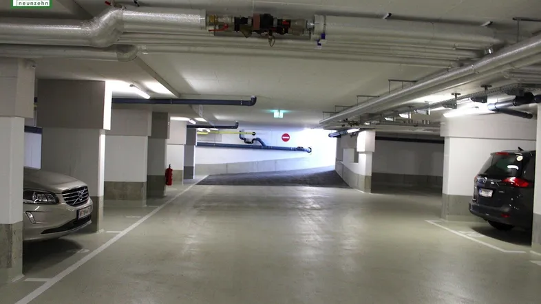 Helle Tiefgarage mit mehreren Stellplätzen und Zufahrtsrampe.
