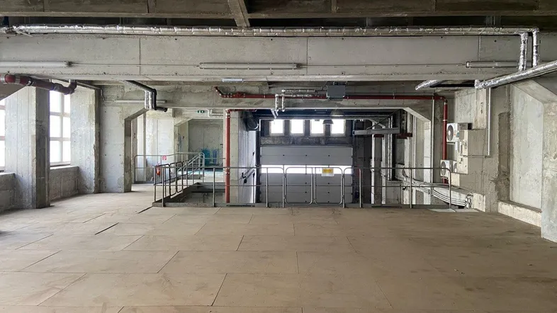 Großer, offener Industrieraum mit hohen Decken, sichtbaren Rohren und Betonpfeilern, bereit für die Nutzung.