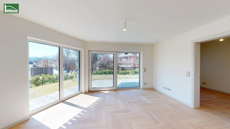 Helles Wohnzimmer mit modernem Fischgrätparkett und Zugang zur Terrasse und zum Garten.