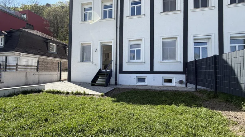 Außenansicht des Gebäudes mit gepflegtem Rasenbereich und Zugang zum Eingangsbereich.