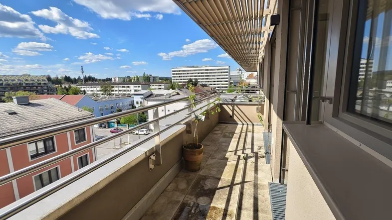 Geräumiger Balkon mit Fliesenboden, Metallgeländer und weitem Blick über die Stadt.