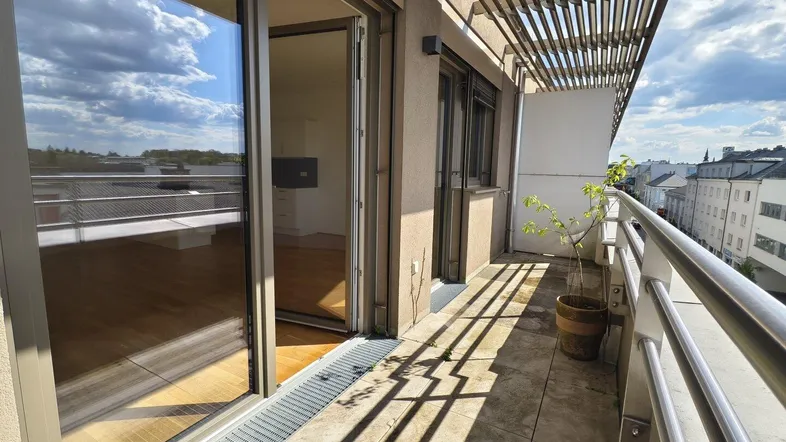 Heller Balkon mit Fliesenboden und Zugang zu den Innenräumen durch große Schiebetüren.