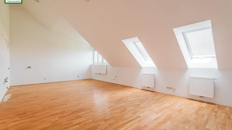 Heller Dachgeschossraum mit Holzboden, schrägen Wänden und Dachfenstern, ideal für individuelle Gestaltung.