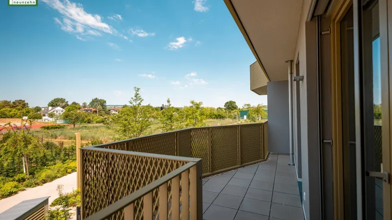 Geräumiger Balkon mit Fliesenboden und Blick ins Grüne sowie auf die umliegende Landschaft.